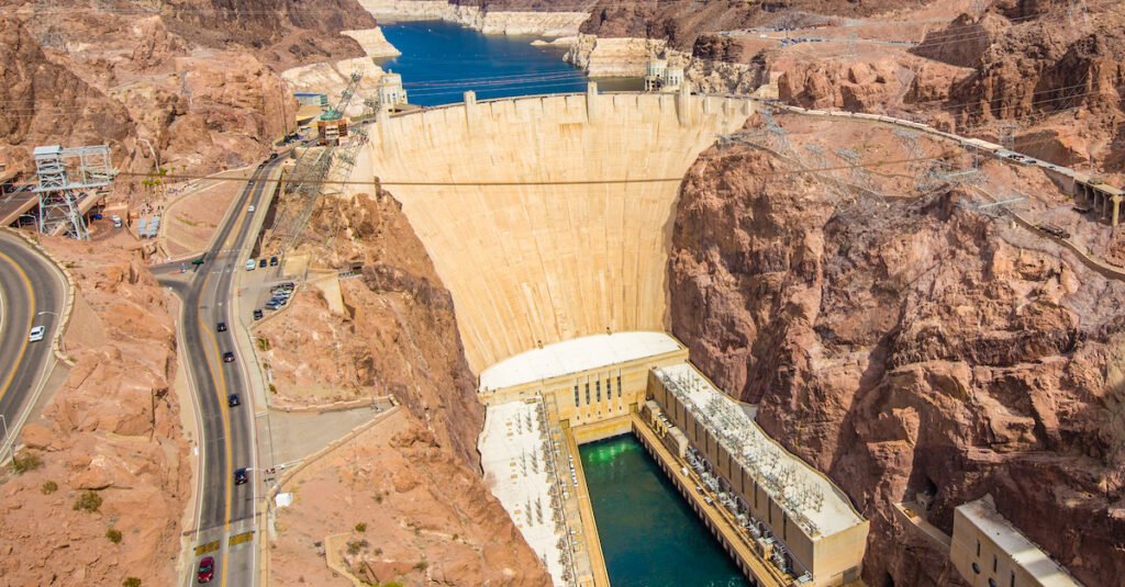 Aerial wide angle view of famous Hoover Dam, a major tourist attraction located on the border between the states of Nevada and Arizona, on a beautiful sunny day with blue sky and clouds in summer, USA
